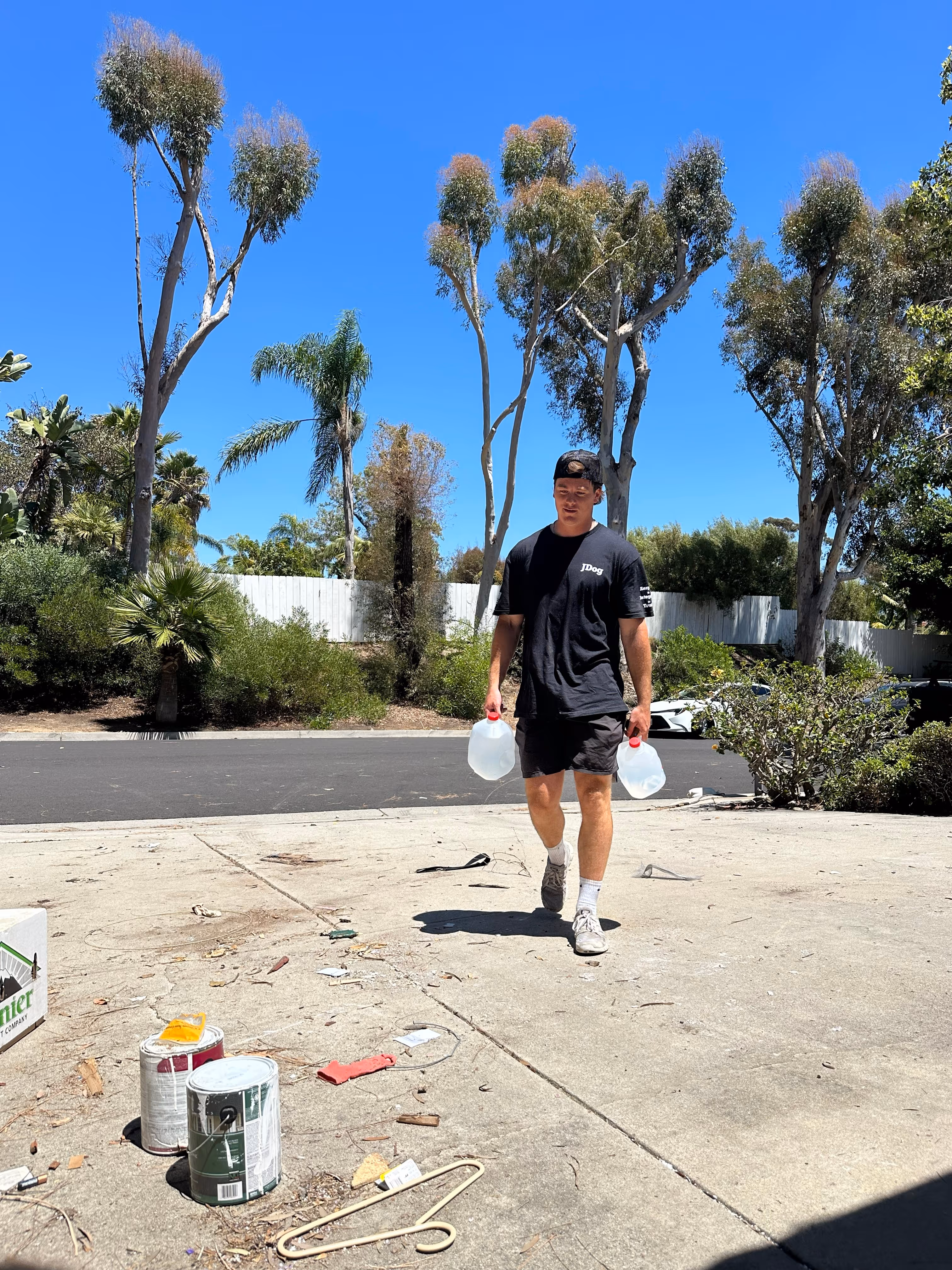 A JDog employee carrying two jugs of water while on-site.