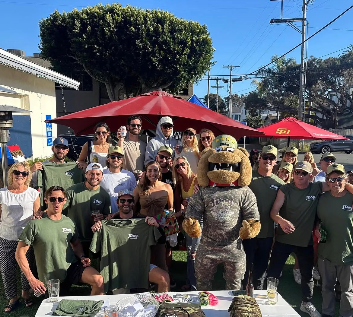 The JDog team and family smiling at a company event with the JDog mascot.