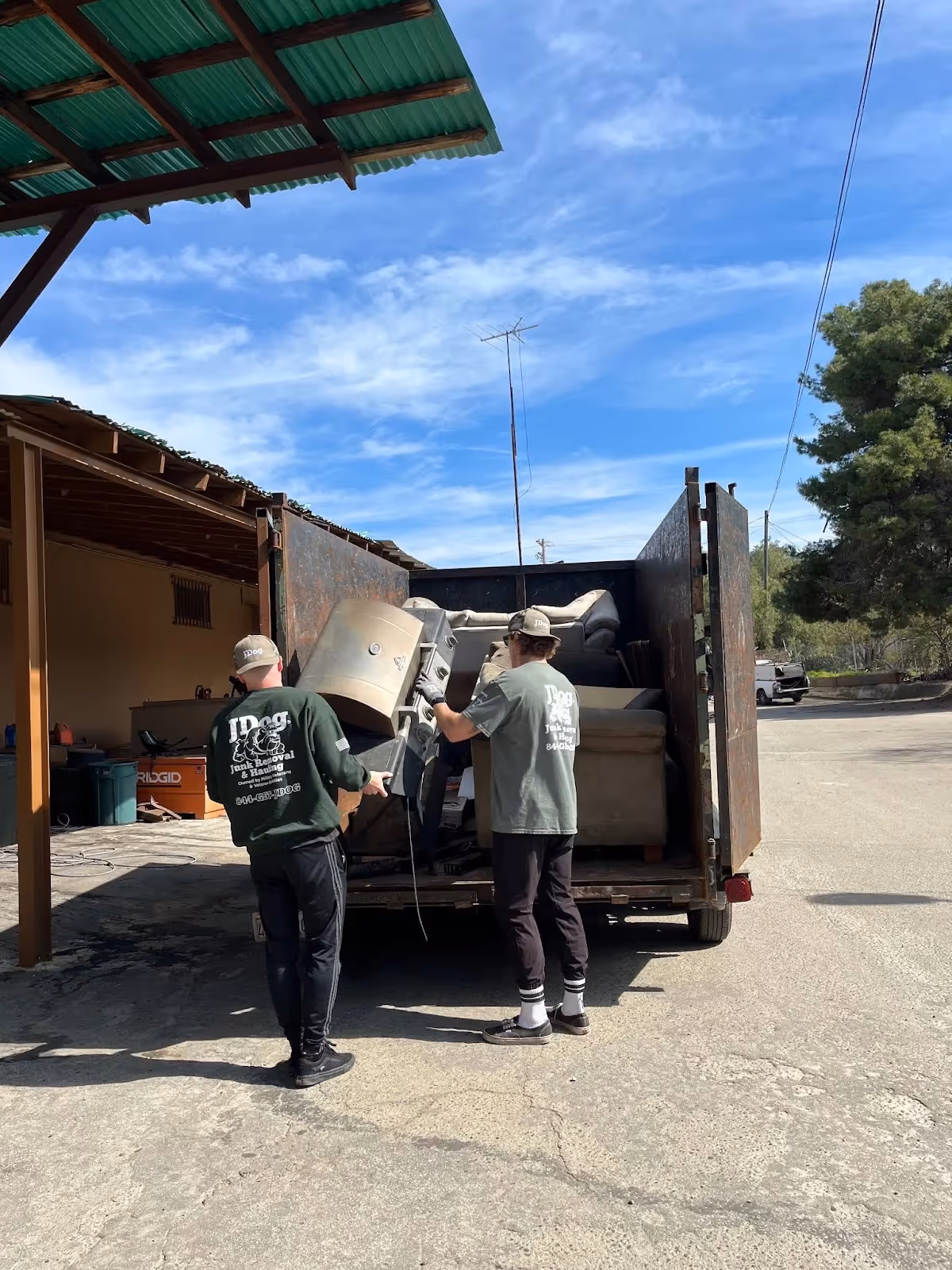 The junk removal crew loading a barbecue grill into the trailer.