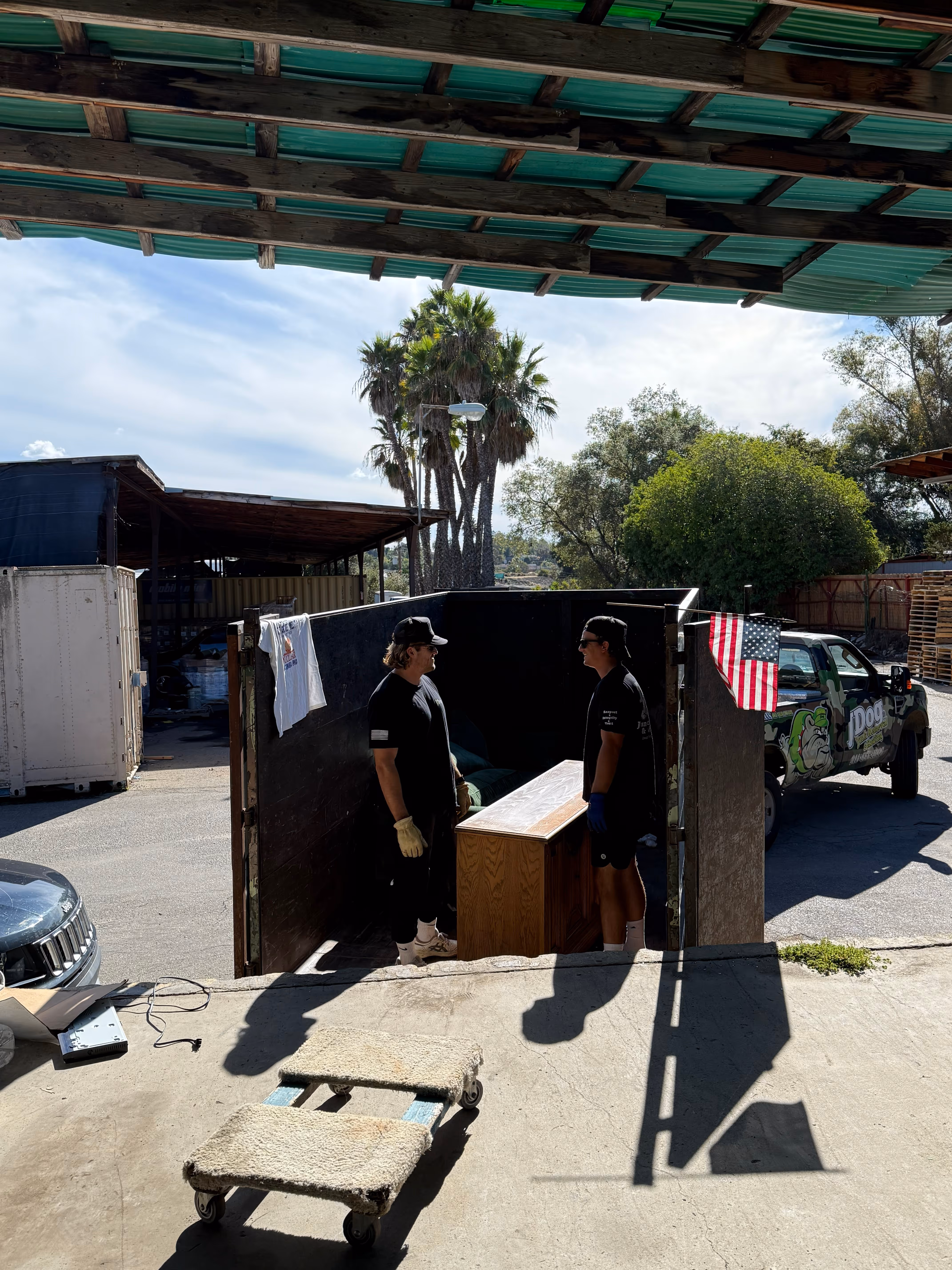Two JDog professionals smiling while loading furniture into the JDog truck.