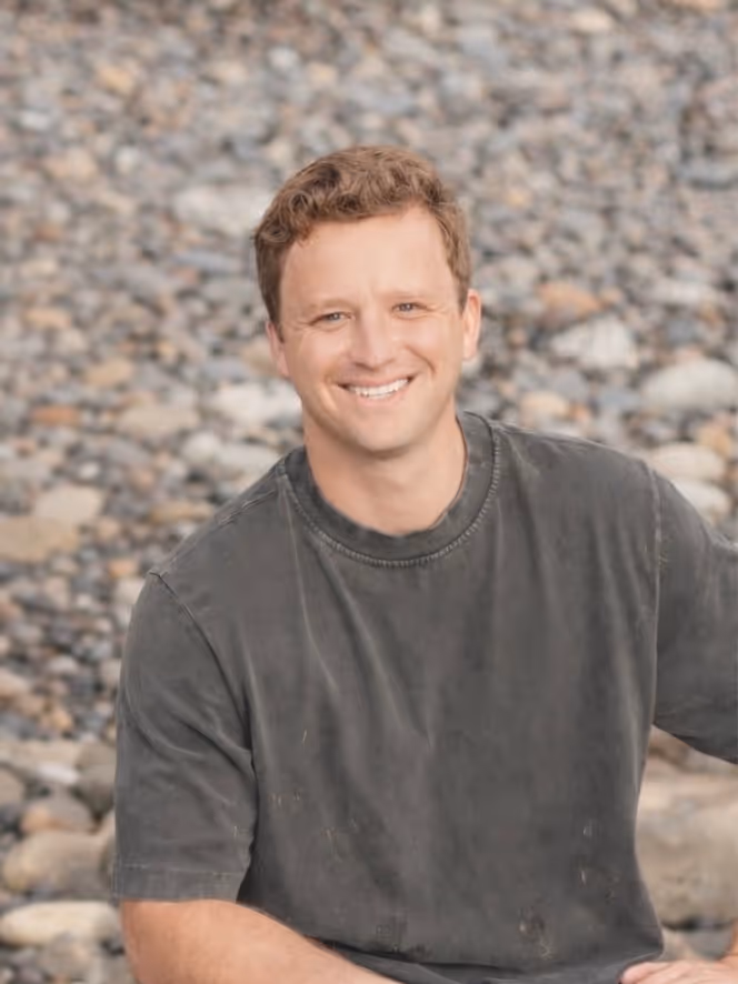 Sam Tapia Smiling on a rocky beach.