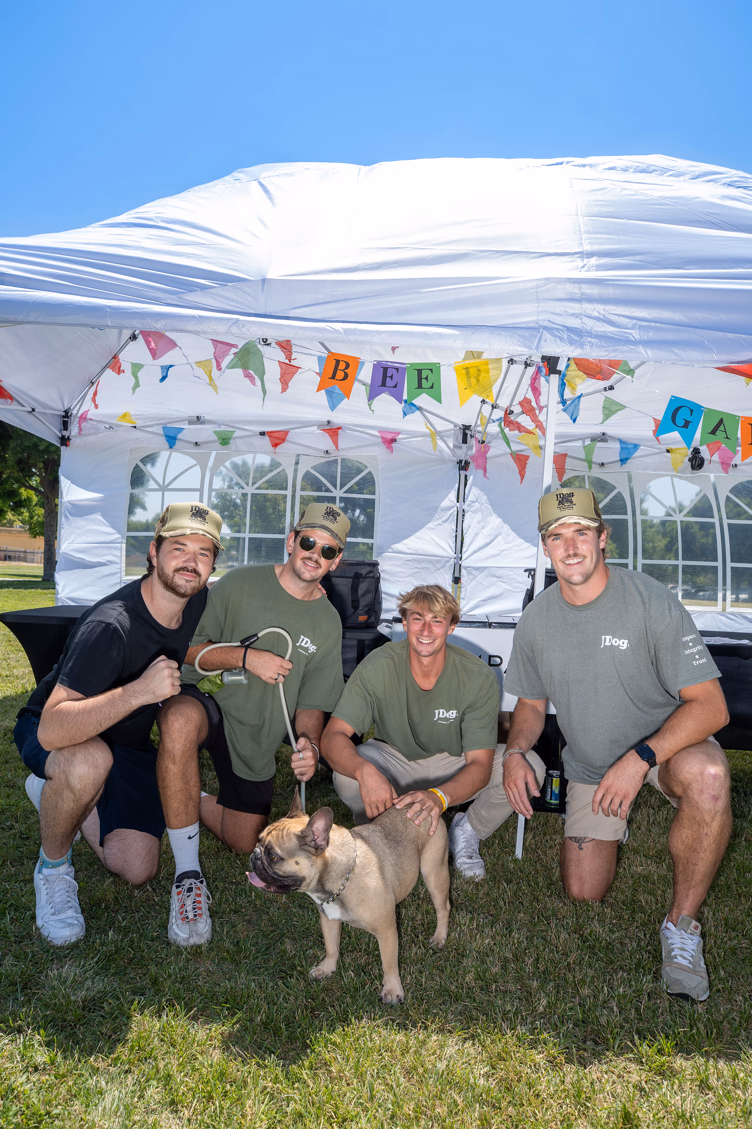 The JDog team at an event posing with a french bulldog.