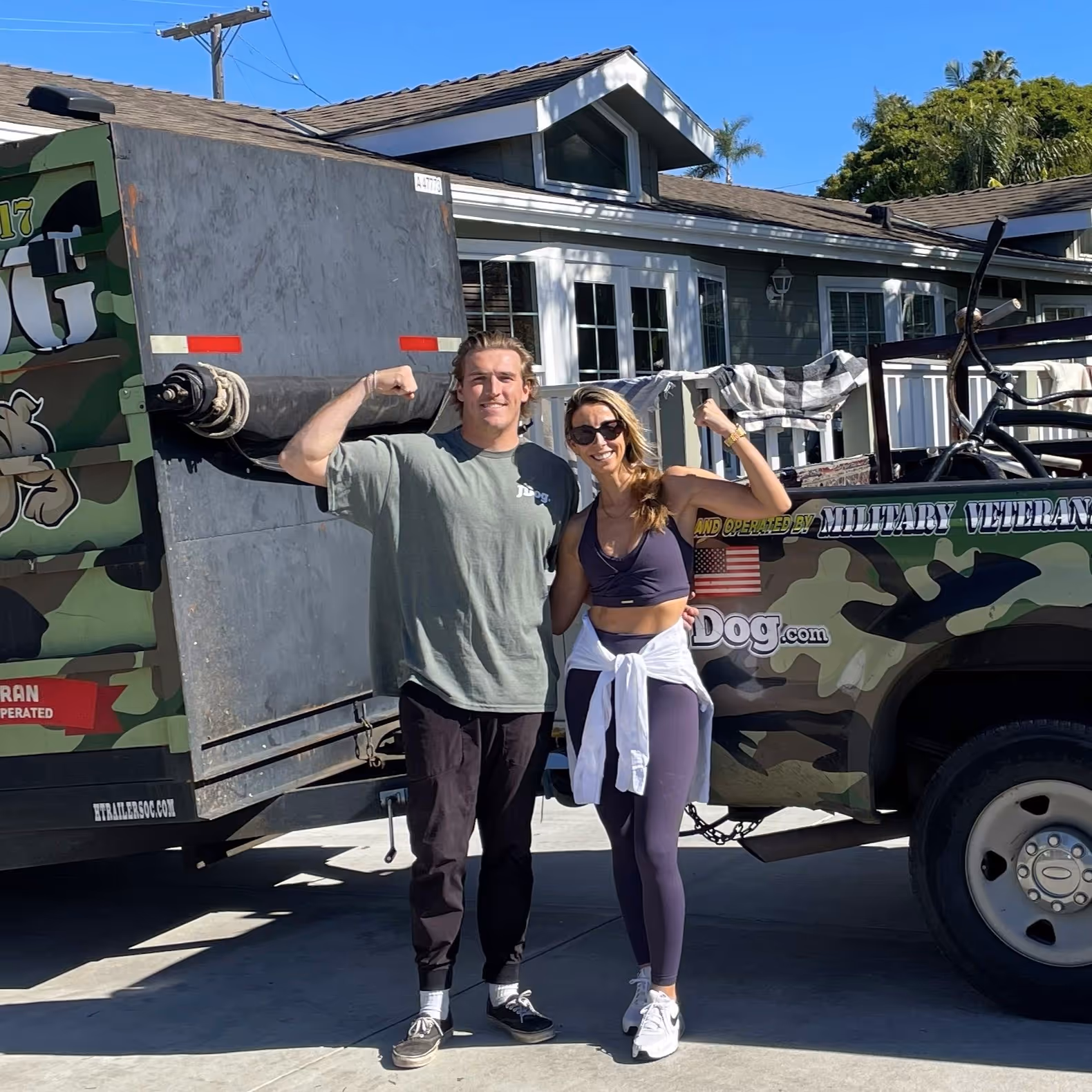 JDog San Diego owner Ryan Fitzpatrick standing next to a female customer, both flexing their biceps.